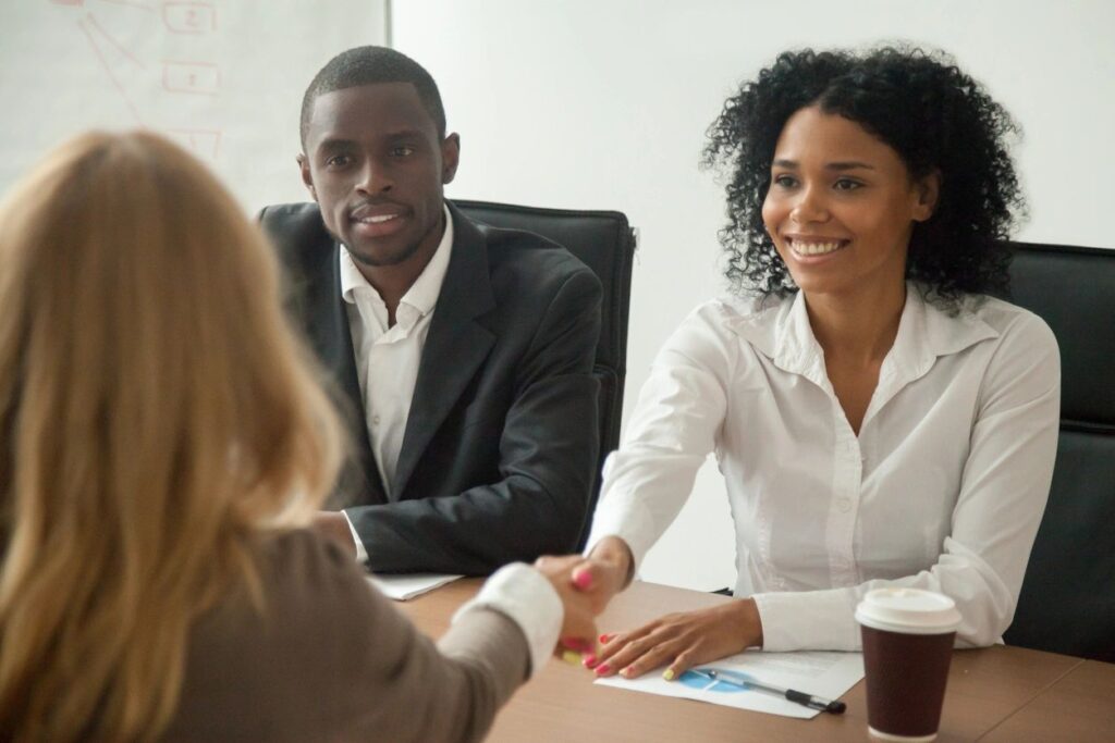 Three people in a business meeting handshake.