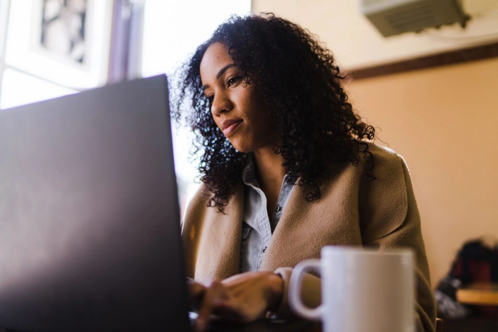 Woman working on laptop with coffee mug.