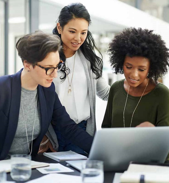 Three women collaborating at a laptop.